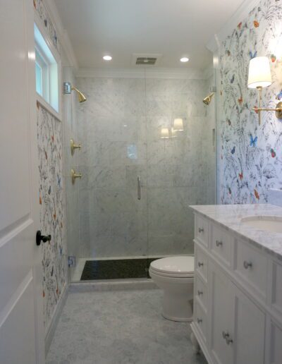 A white bathroom with floral wallpaper and a walk in shower.