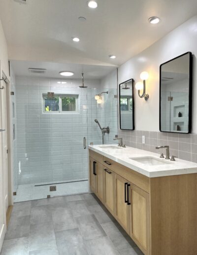 A bathroom with two sinks and a shower.