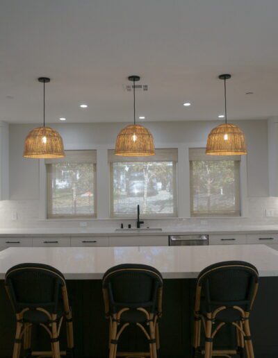 A kitchen with a white island and black stools.